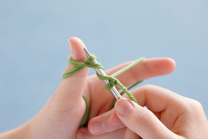 Insert the needle tip up under the two doubled tails on the thumb.